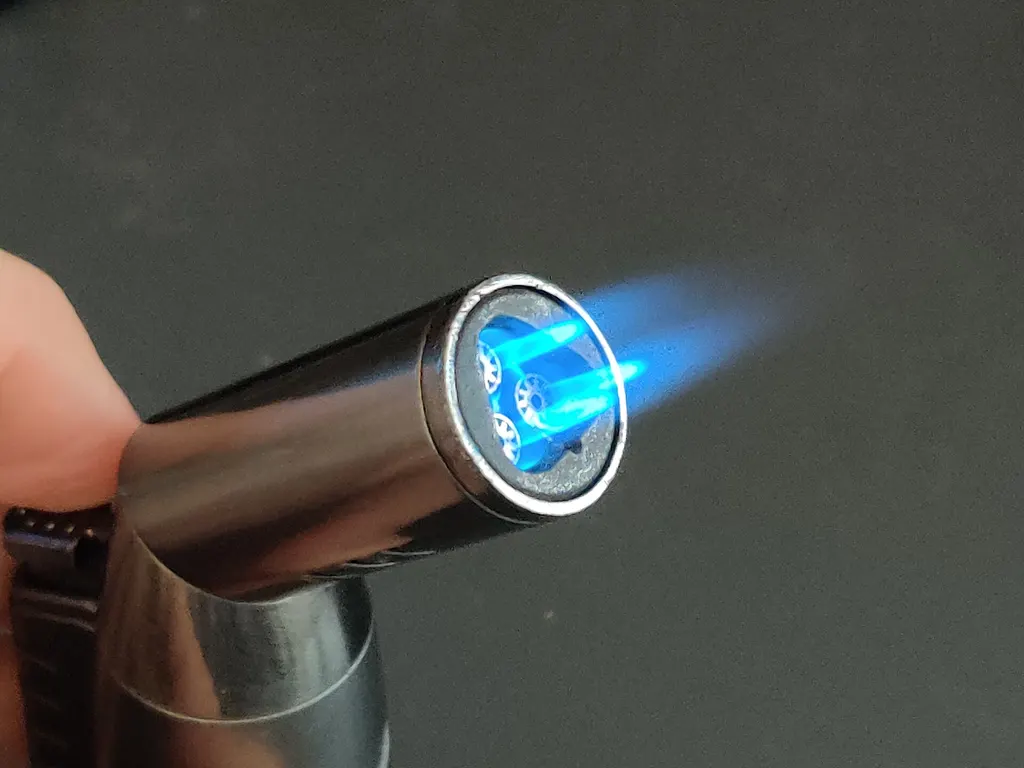 A triple-jet torch lighter burning with three blue flames