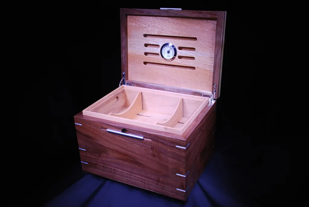 An open walnut desktop humidor with a Spanish cedar tray and a dial hygrometer in the lid