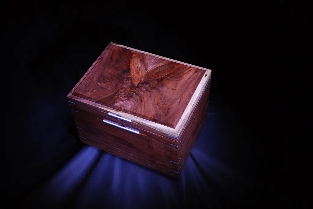 A walnut humidor with a figured, bookmatched lid on a dark background